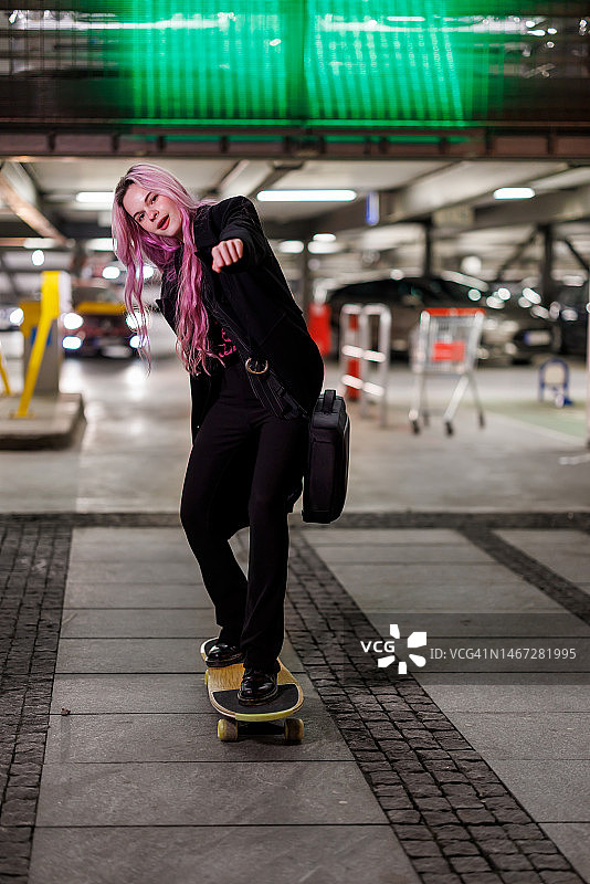 美女在夜间城市街道上玩滑板图片素材