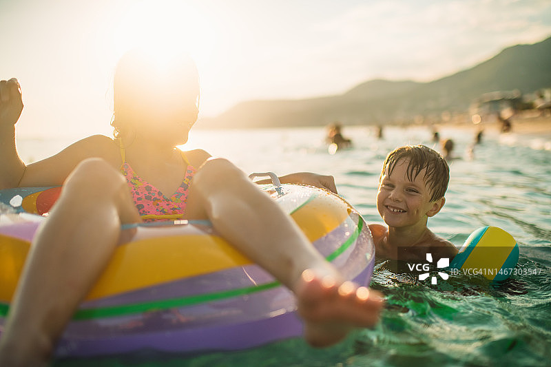 孩子们在暑假玩耍，在海里游泳、嬉戏和玩充气游泳圈图片素材