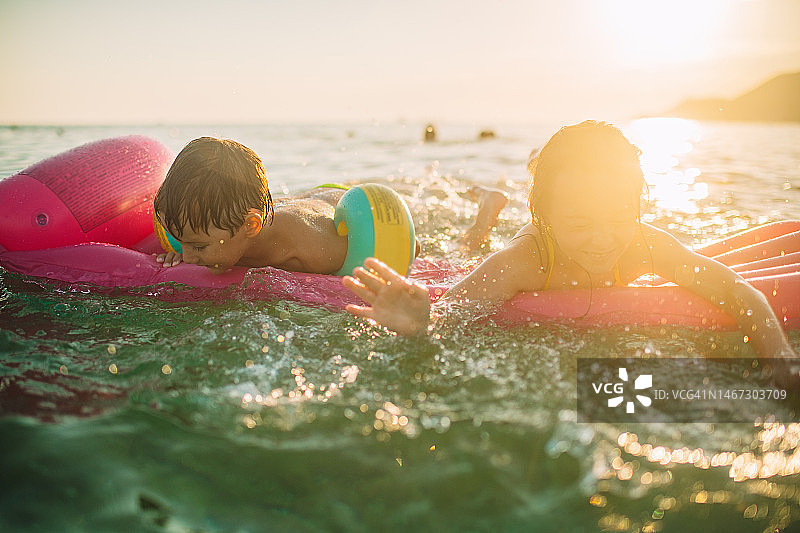 孩子们在暑假玩耍，在海里游泳、嬉戏和玩充气游泳圈图片素材
