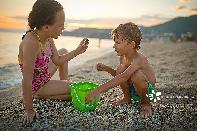夏日海滩假期，小男孩和女孩捡拾贝壳图片素材