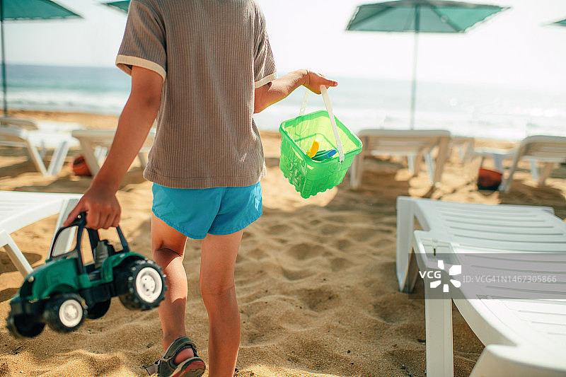 夏天海滩度假时孩子在海边玩沙滩玩具图片素材