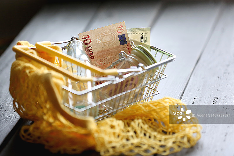 黄色可重复使用购物袋和带有两张欧元纸币的空购物车图片素材