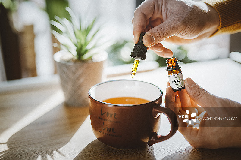 男子将CBD油滴入茶杯中图片素材