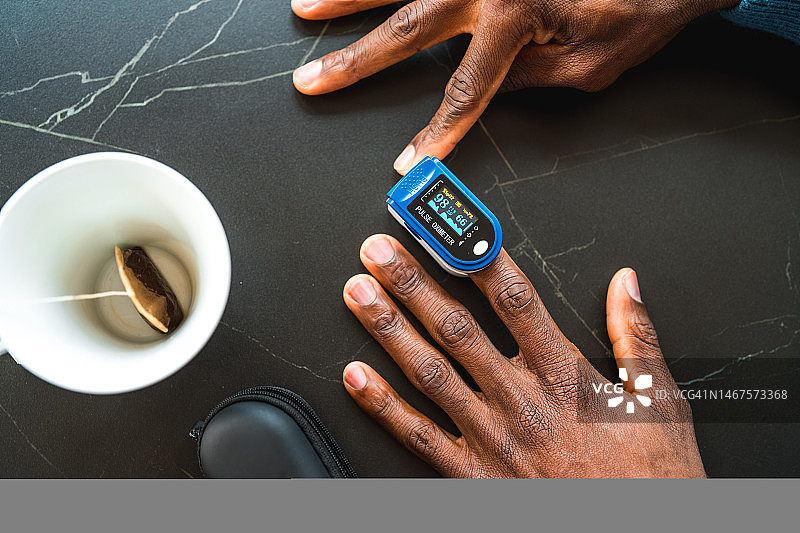 黑人男子在家使用脉搏血氧仪图片素材