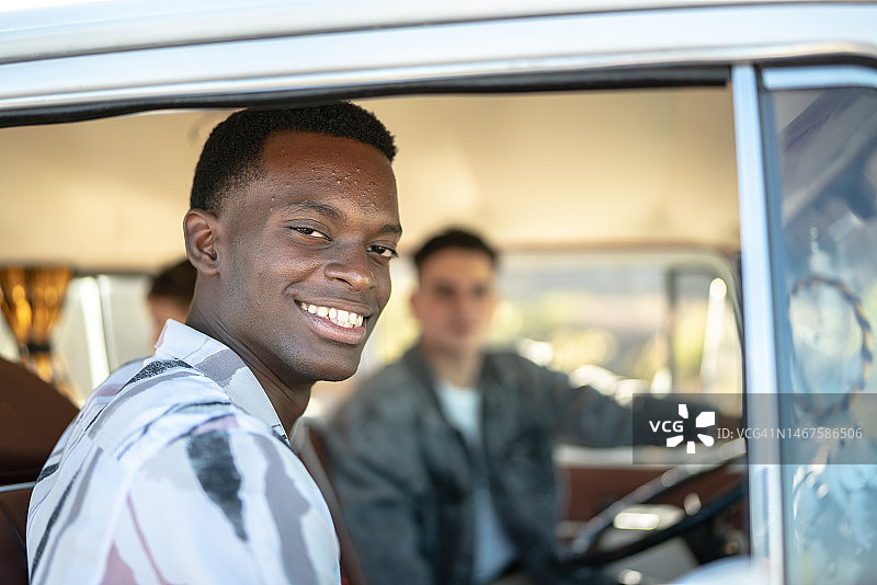 复古迷你货车公路旅行中的青年男子肖像图片素材