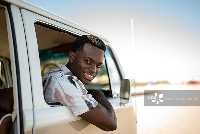 复古迷你货车公路旅行中的青年男子肖像图片素材