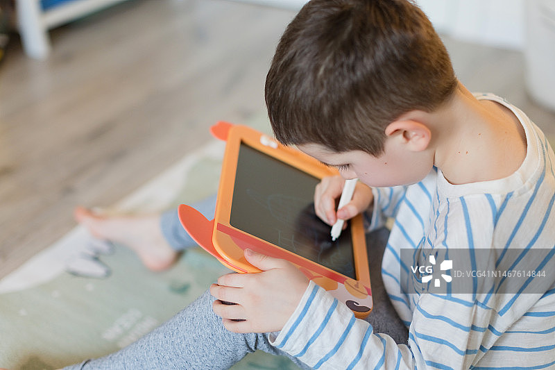 男孩在室内用绘图板绘画图片素材