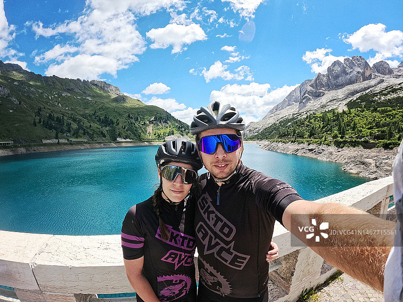 在多洛米蒂山享受骑自行车并自拍的年轻情侣图片素材