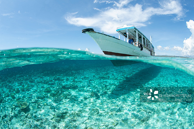 漂浮在印度尼西亚瓦卡托比国家公园水晶般清澈的海面上的船只图片素材