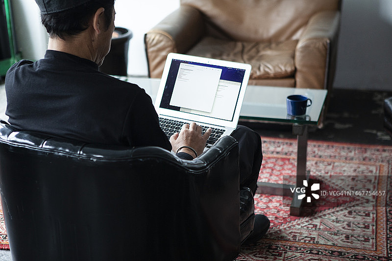 沉思的男人在办公室里用笔记本电脑工作图片素材