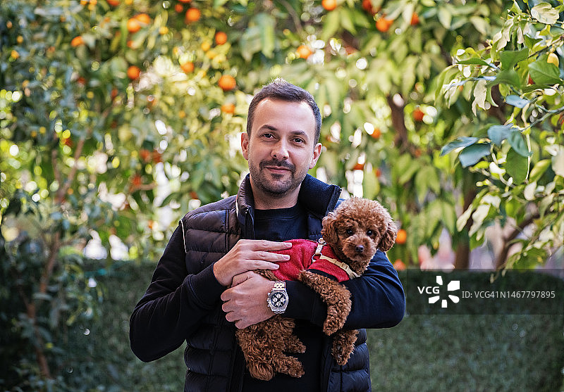 在房子外面拥抱他的狗的男人肖像图片素材