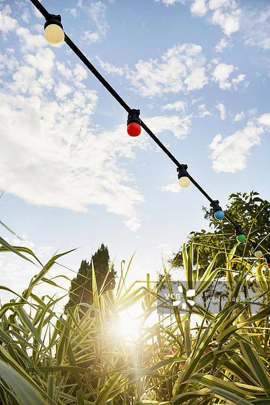 派对装饰用彩色串灯，背景是天空和阳光图片素材