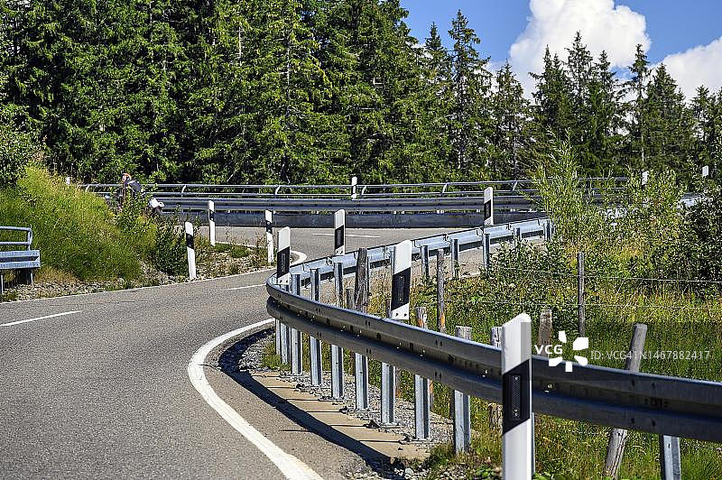 在德国巴伐利亚阿尔高巴尔德施旺山谷的道路上，摩托车骑行者在S弯道上行驶图片素材