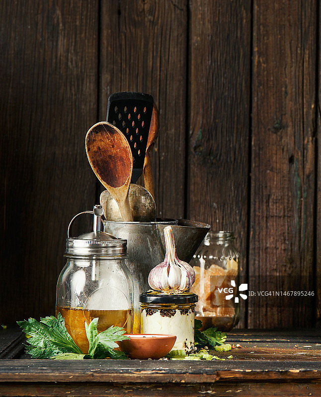 乡村食物静物与橄榄油罐，大蒜，香草，香料和木桌上的老式厨房用具图片素材