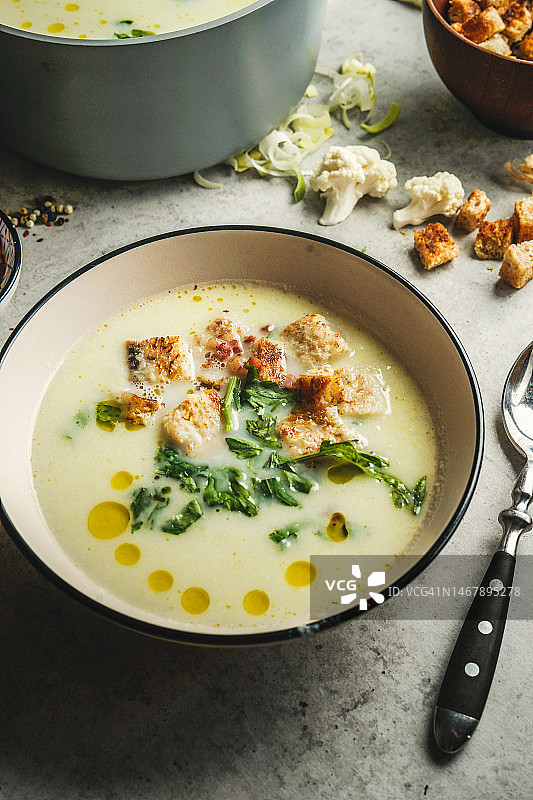 美味奶油菜花汤碗，配面包丁、新鲜香草和油滴图片素材