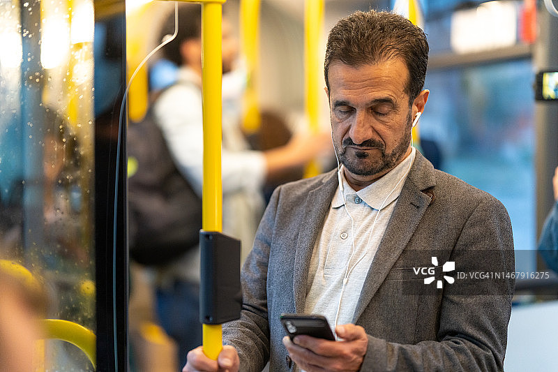 在公交车上听音乐和使用智能手机的男人图片素材