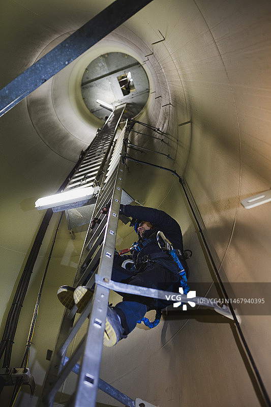 风力涡轮机工程师扶着梯子，并用生命线保护，防止坠落图片素材