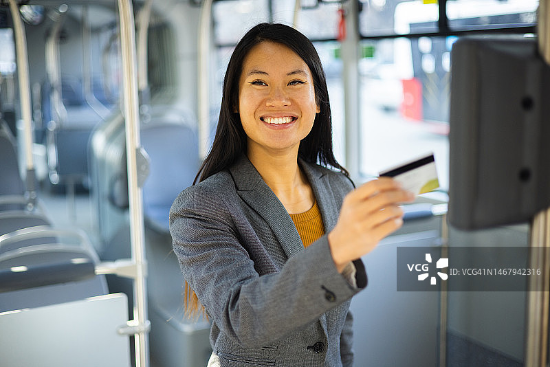 快乐的亚洲女人在公交车上买票的 портрет图片素材