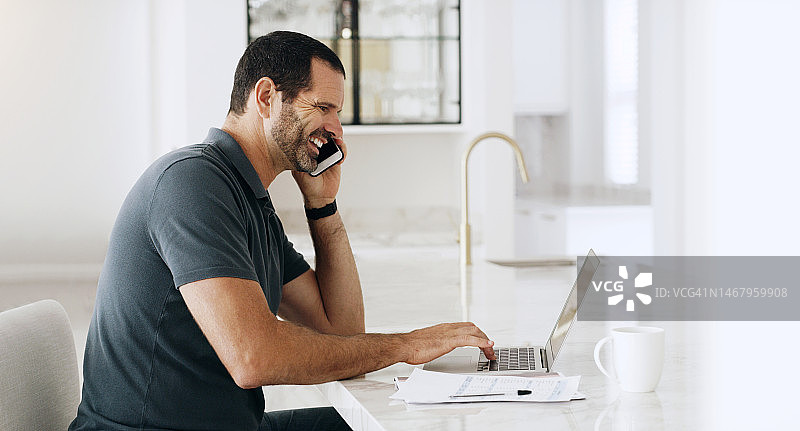 男人居家远程办公，使用手机和电脑通话图片素材