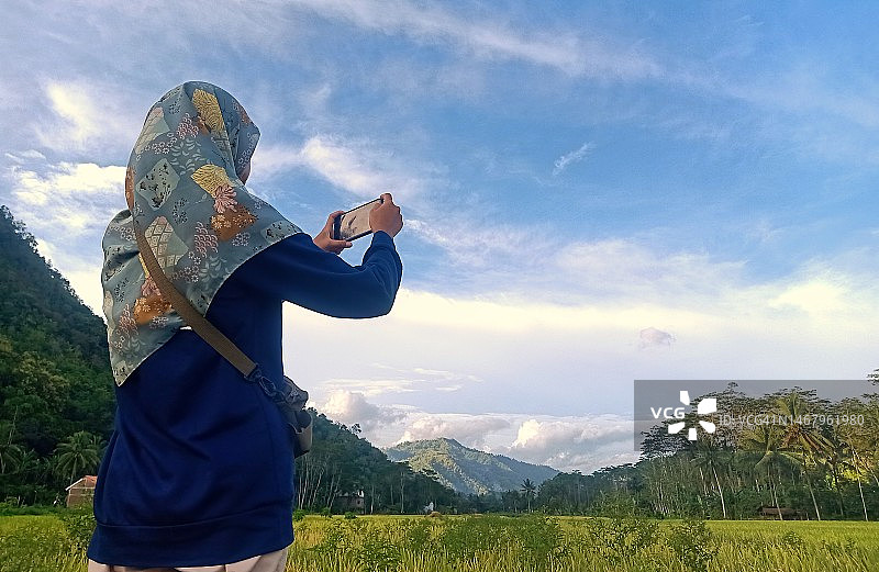 在乡村自然环境中用手机的戴头巾的女人图片素材