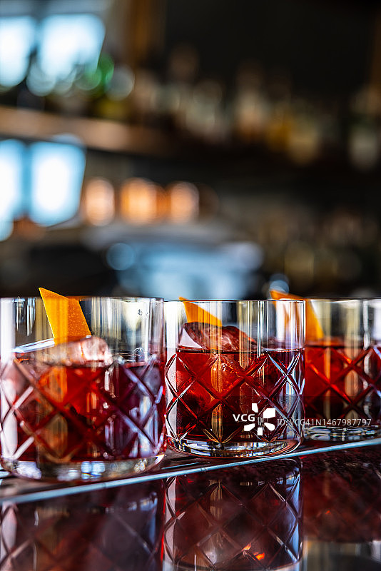 吧台上三杯尼格罗尼鸡尾酒和金酒图片素材