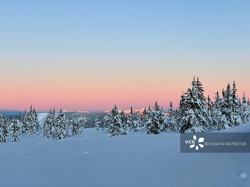 山区中柔和色彩的迷人冬季日落，白雪皑皑图片素材