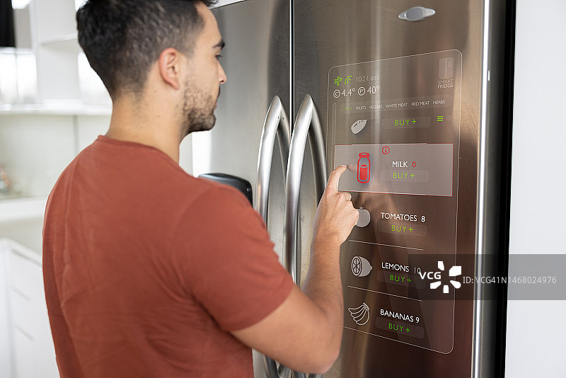 男人在他的智能家居冰箱上看购物清单图片素材