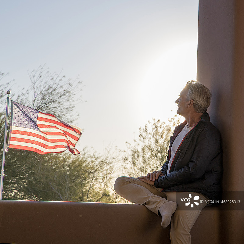 年长的男人在美国国旗附近的墙上放松图片素材
