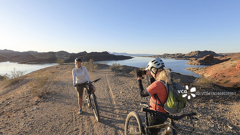 中年山地自行车女骑手在湖上拍照图片素材