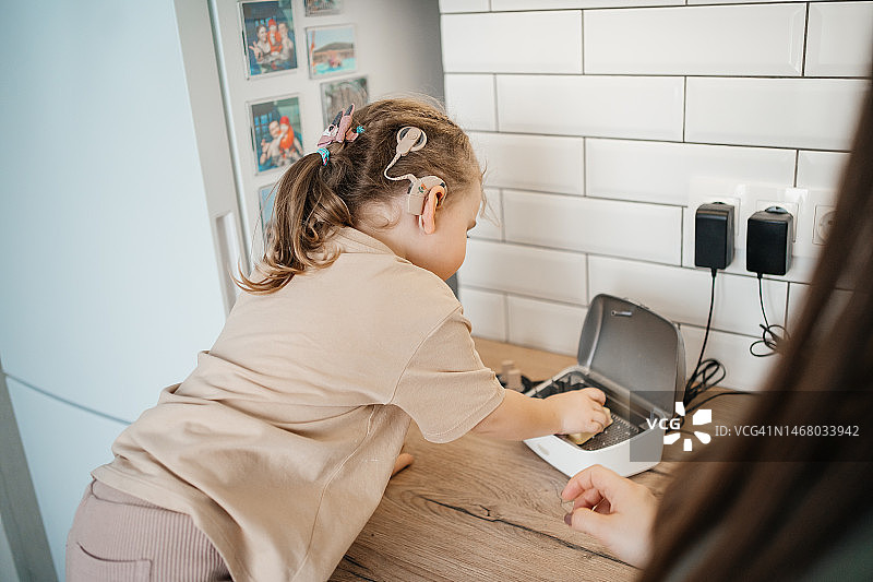 孩子给人工耳蜗电池充电图片素材