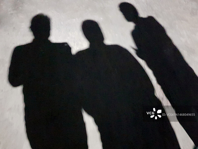 灰色地面上站立的三个朋友的影子图片素材