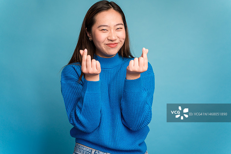 指向镜头，做出要钱手势的年轻女人图片素材