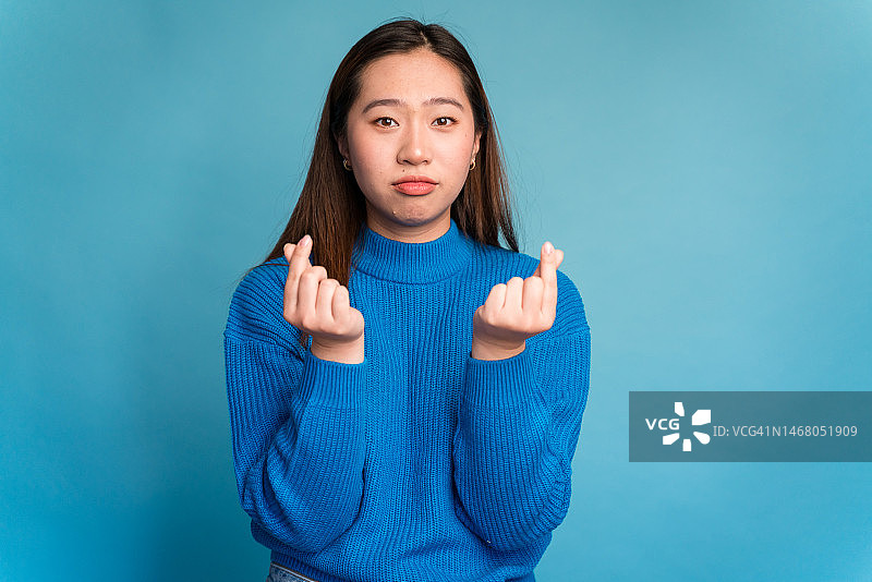 指向镜头，做出没钱手势的年轻女子图片素材