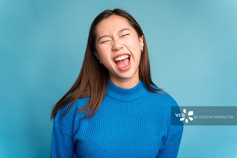 快乐的年轻女子闭着眼睛对着镜头尖叫图片素材