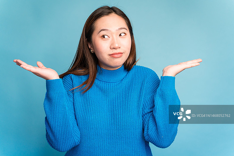 穿着毛衣的亚洲女人做出不确定的手势图片素材