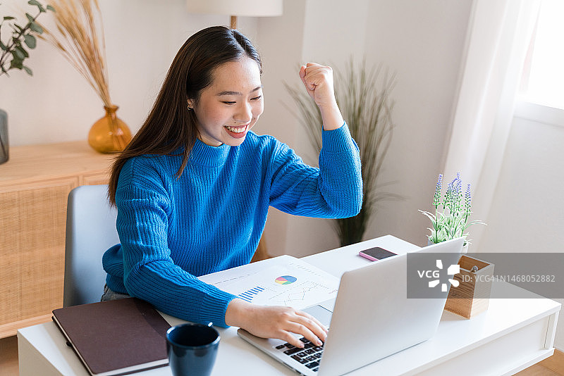 用笔记本电脑庆祝好消息的微笑女性图片素材