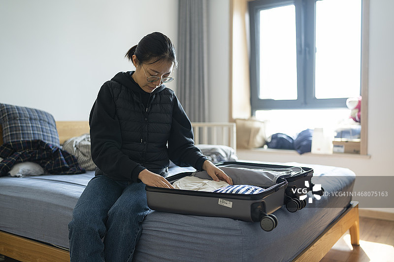 正在整理衣服和行李箱，准备旅行的亚裔女人图片素材