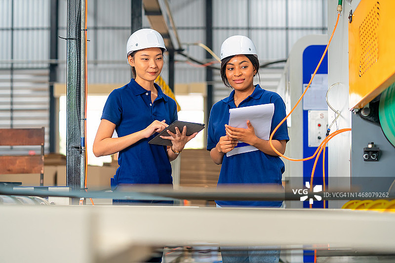 绩效评估必须包含大量工作示例。女性质量和数量工程师团队合作检查纸箱内部过程生产线上印刷的质量和数量。图片素材