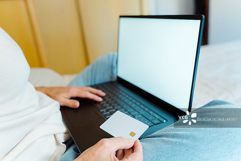 女士在家用信用卡和电脑进行网上购物图片素材