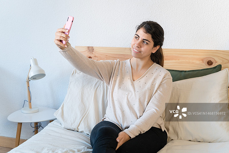 女人在公寓的床上用手机自拍，简约风格图片素材