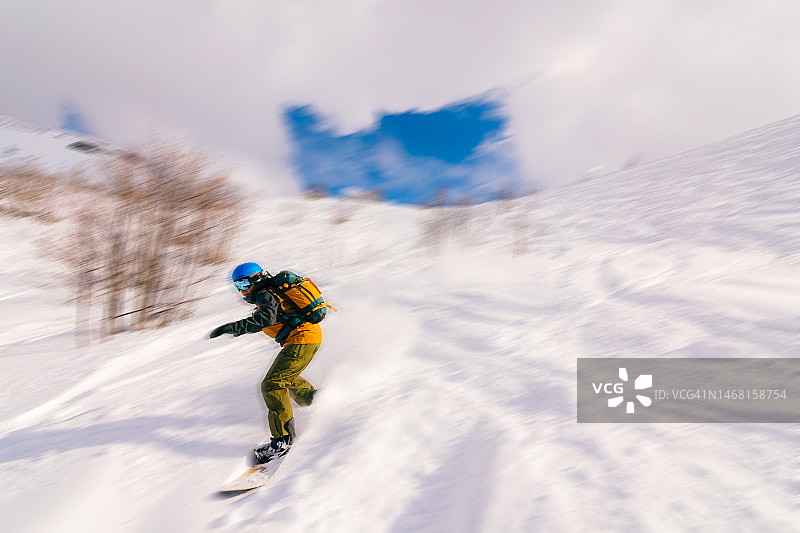 阳光明媚的日子里，滑雪者在山中滑行，运动模糊图片素材