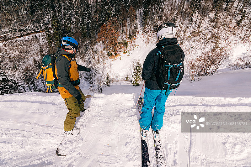 滑雪者和滑雪者站在滑雪道的边缘，眺望远方图片素材
