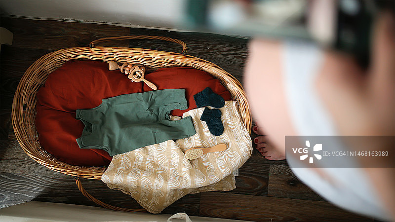 天然柳条篮、木制拨浪鼓和新生婴儿环保棉衣图片素材