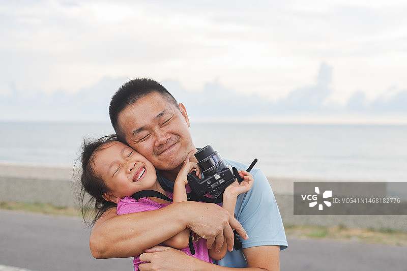 亚洲父亲和女儿坐在海边玩耍图片素材