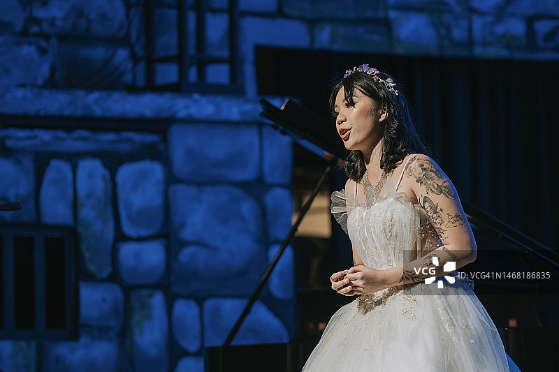 年轻的中国女歌唱家在舞台上独唱图片素材