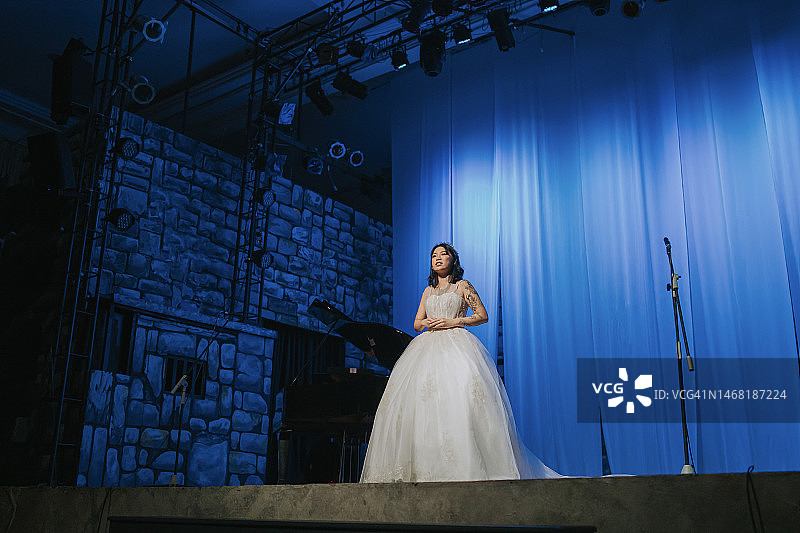 年轻的中国女歌唱家在舞台上独唱图片素材