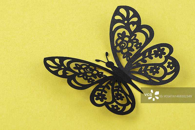 黄色纸背景上的黑色蝴蝶，带有设计用的复制空间图片素材