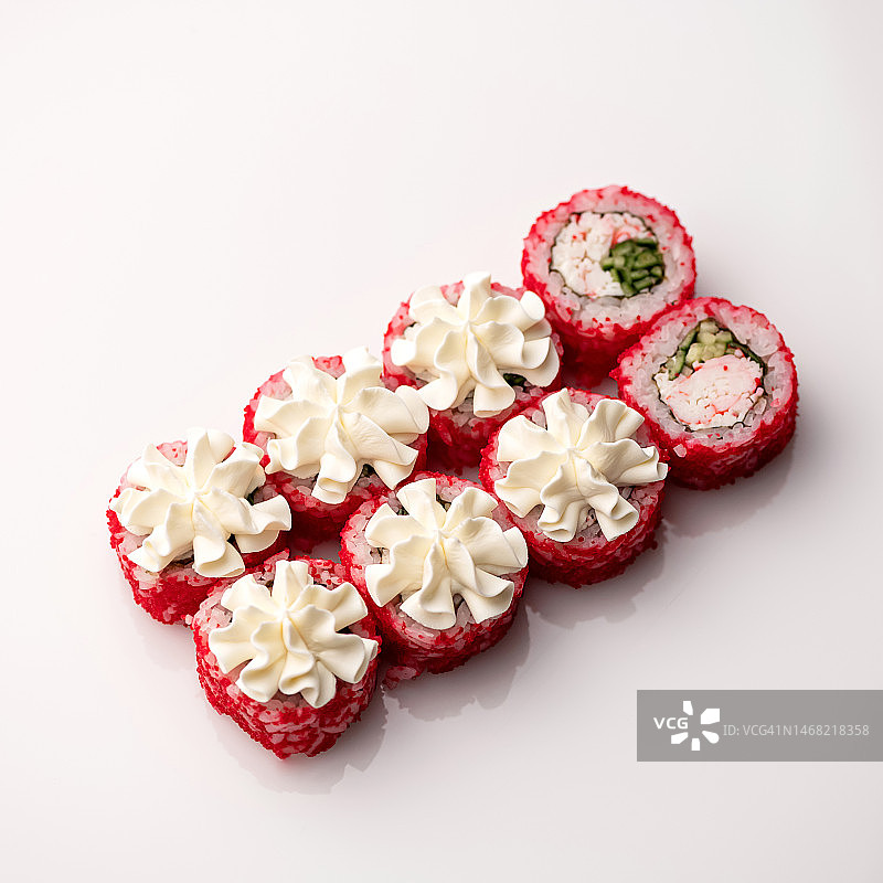配有亮粉色飞鱼籽、黄瓜和蟹肉的寿司卷，顶部装饰奶油奶酪，日式料理，白色背景，顶部视角，留白图片素材
