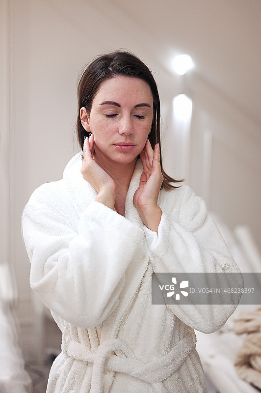 中年妇女在衣柜里用面霜按摩脸部图片素材