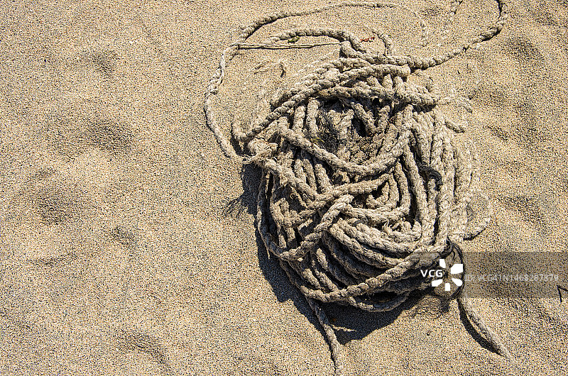 沙滩上被丢弃的盘绕绳索图片素材